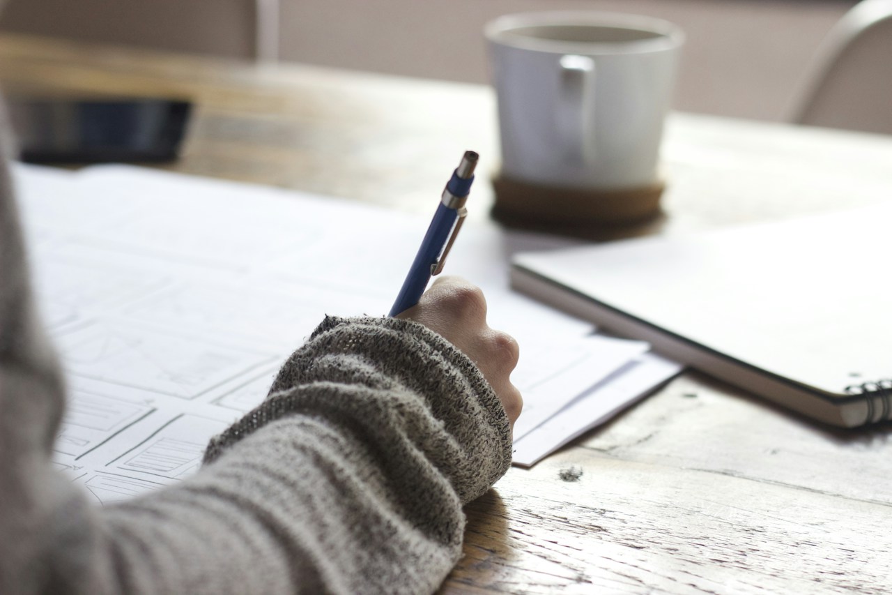 Open notebook with handwritten budget categories beside a pen